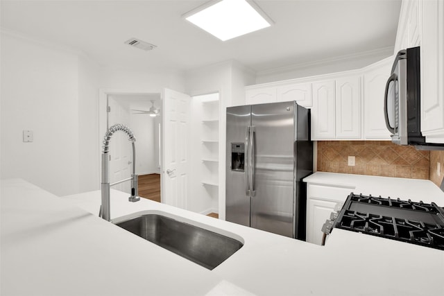 kitchen featuring stainless steel appliances, a sink, white cabinetry, light countertops, and backsplash