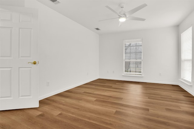 spare room featuring baseboards, ceiling fan, visible vents, and wood finished floors