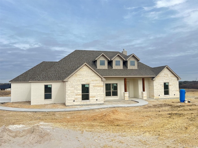 view of front facade featuring stone siding and a shingled roof