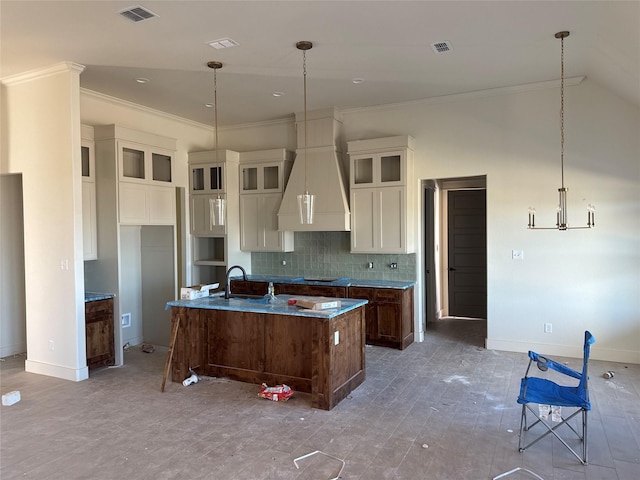 kitchen featuring sink, backsplash, ornamental molding, an island with sink, and custom exhaust hood