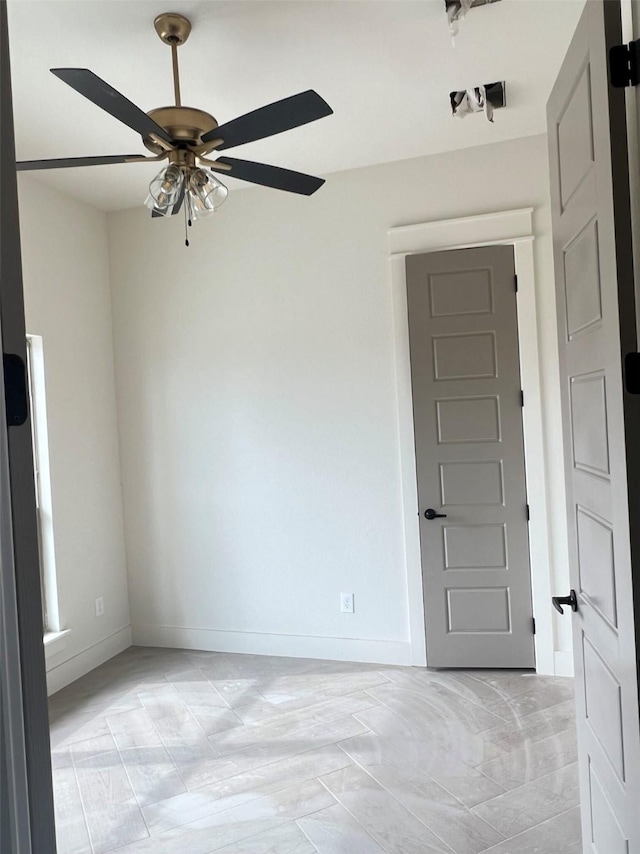 spare room with baseboards and a ceiling fan