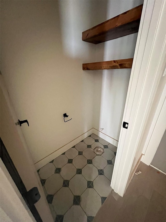 clothes washing area featuring tile patterned floors and baseboards