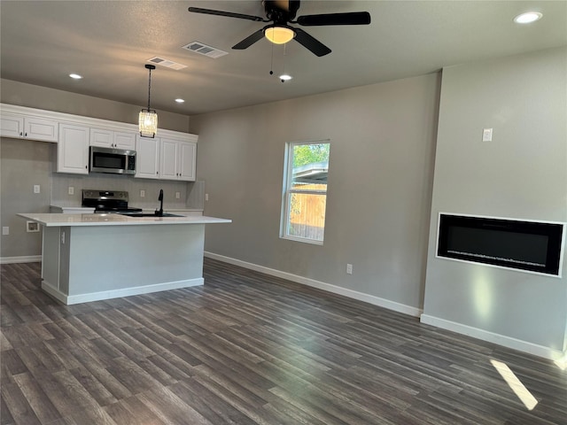 kitchen featuring hanging light fixtures, stainless steel appliances, dark hardwood / wood-style floors, an island with sink, and white cabinets