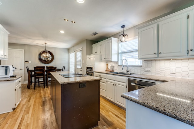 kitchen with decorative light fixtures, a center island, sink, and white cabinets