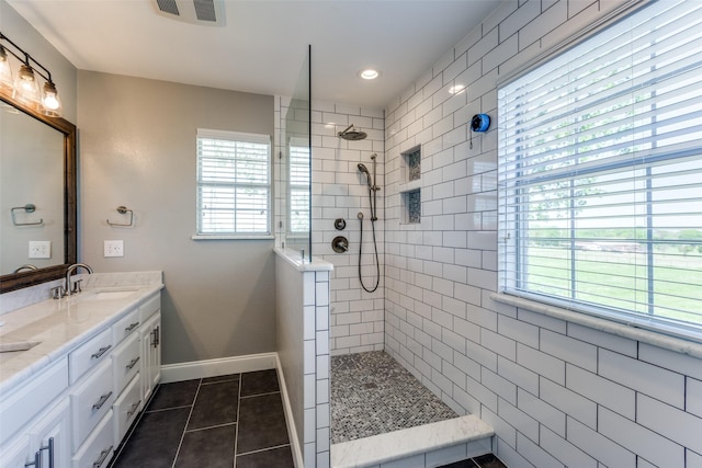 bathroom with vanity, a tile shower, and tile patterned floors