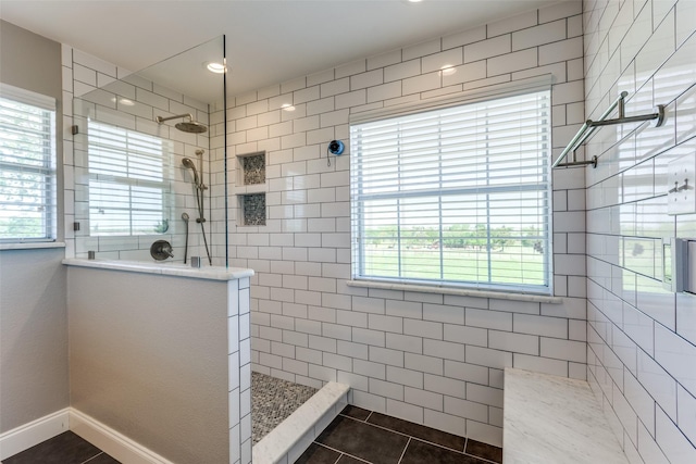 bathroom with tile patterned flooring, a healthy amount of sunlight, and tiled shower