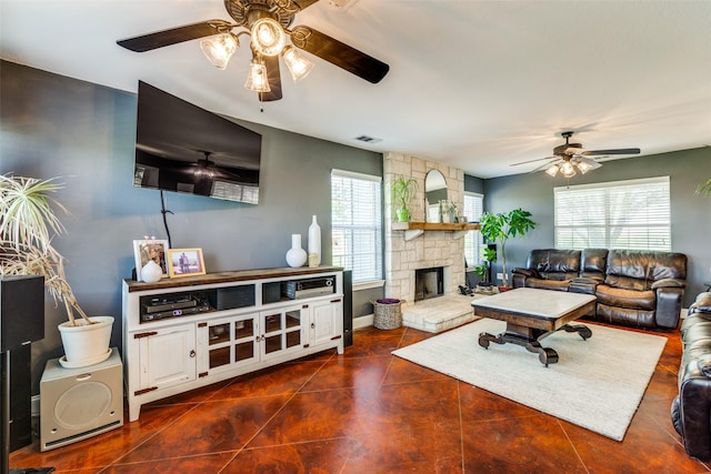 living room with a fireplace, plenty of natural light, ceiling fan, and dark tile patterned flooring