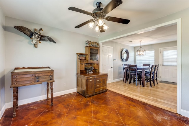 dining space with dark hardwood / wood-style flooring and ceiling fan with notable chandelier