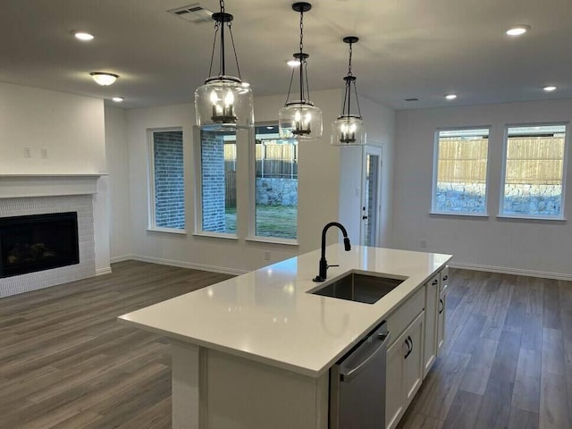 kitchen with sink, white cabinetry, decorative light fixtures, dishwasher, and a kitchen island with sink