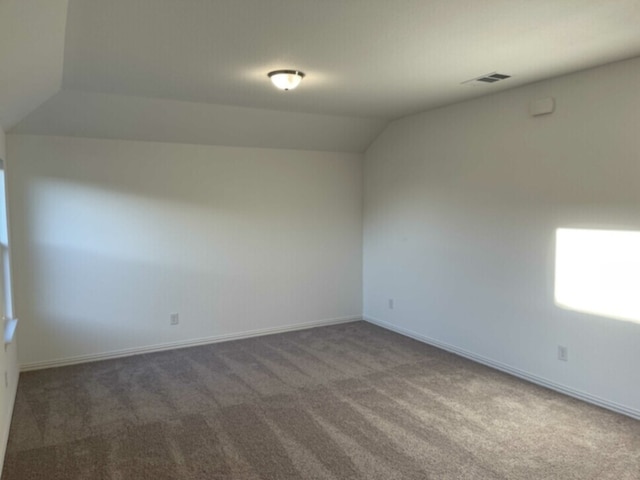 carpeted empty room with lofted ceiling