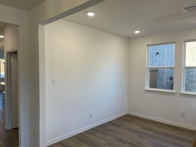 empty room with dark wood-style floors, baseboards, visible vents, and recessed lighting