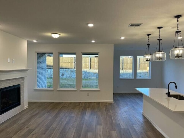 unfurnished living room featuring dark wood-style flooring, a fireplace, a sink, and baseboards