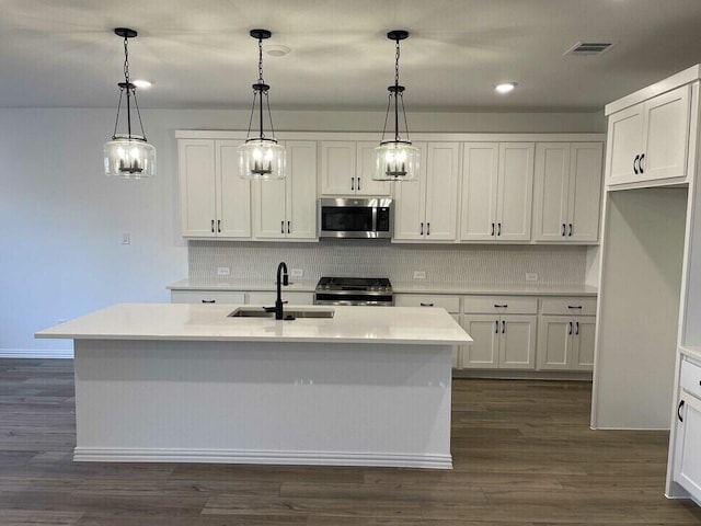 kitchen with appliances with stainless steel finishes, sink, a center island with sink, and decorative light fixtures