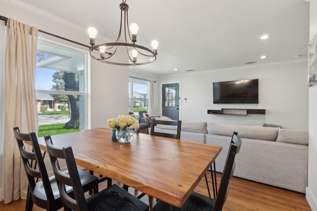 dining area with an inviting chandelier, crown molding, and wood-type flooring