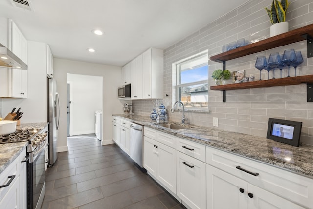 kitchen with light stone countertops, appliances with stainless steel finishes, sink, and white cabinets