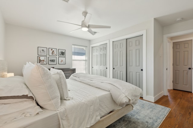 bedroom featuring multiple closets, ceiling fan, and dark hardwood / wood-style floors