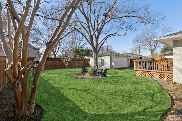 view of yard with an outbuilding, a garage, a deck, and a fire pit