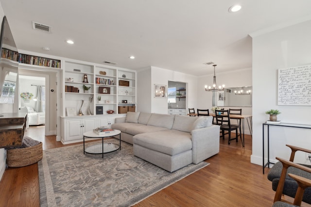 living room featuring an inviting chandelier, crown molding, and wood-type flooring