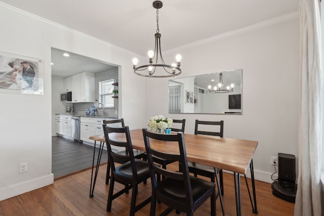 dining area featuring an inviting chandelier, sink, crown molding, and dark wood-type flooring