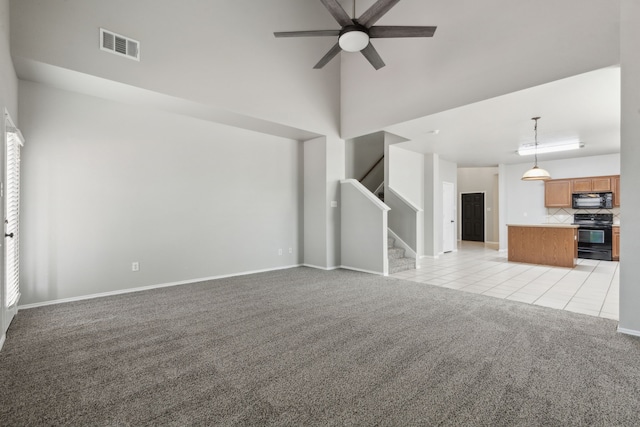 unfurnished living room featuring ceiling fan, light colored carpet, and a towering ceiling