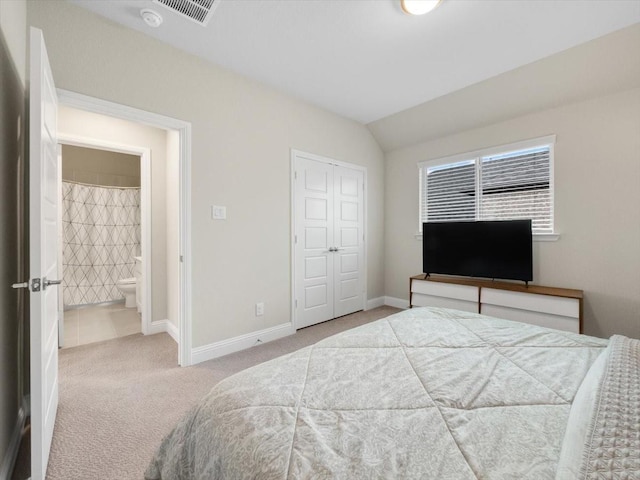 bedroom featuring lofted ceiling, light colored carpet, connected bathroom, and a closet