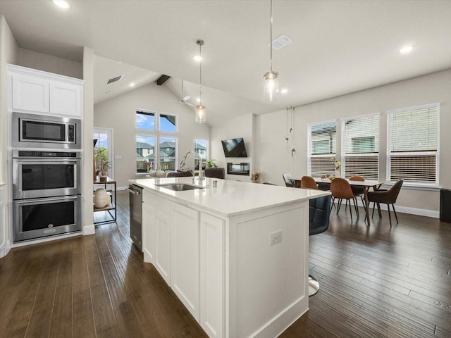 kitchen featuring pendant lighting, sink, white cabinetry, dark hardwood / wood-style floors, and a center island with sink