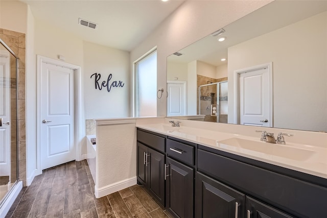 bathroom featuring vanity, hardwood / wood-style floors, and plus walk in shower