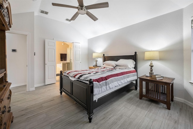 bedroom with ceiling fan, lofted ceiling, wood-type flooring, and a barn door