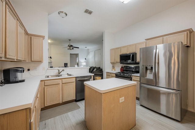 kitchen featuring sink, a center island, stainless steel appliances, light hardwood / wood-style floors, and decorative backsplash