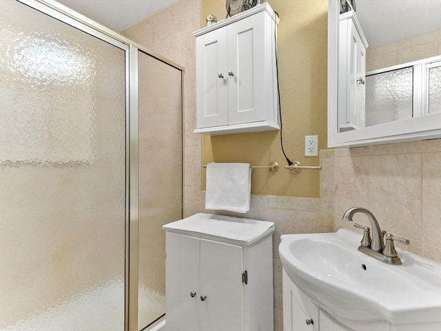 bathroom featuring a shower with shower door, sink, and tile walls