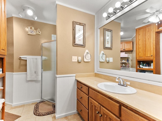 bathroom with tile patterned flooring, vanity, an enclosed shower, ceiling fan, and crown molding