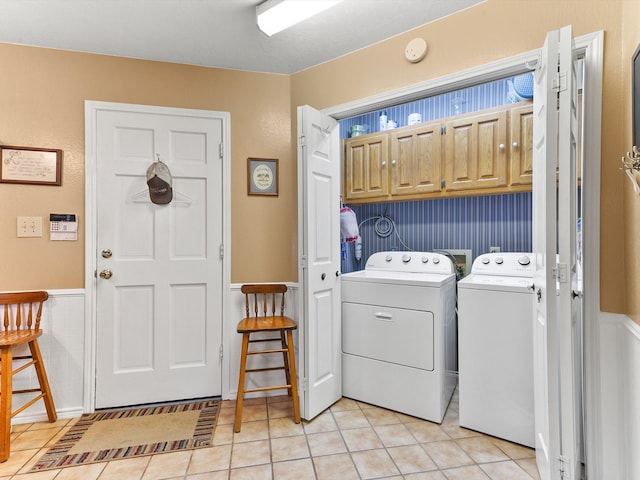 clothes washing area with cabinets, light tile patterned floors, and washing machine and clothes dryer