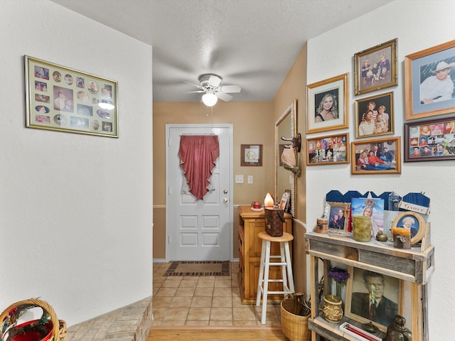 foyer featuring light tile patterned flooring, ceiling fan, and a textured ceiling