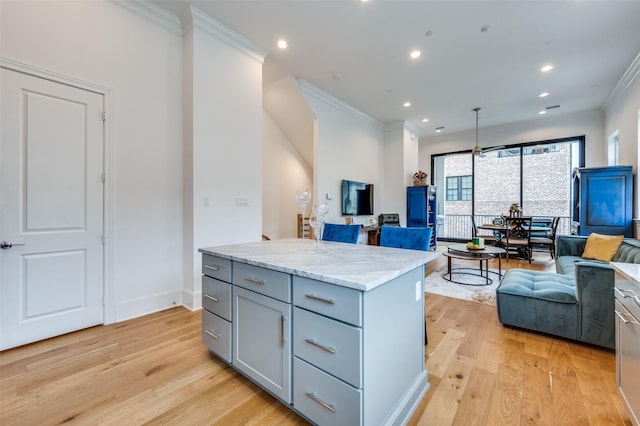 kitchen with pendant lighting, light hardwood / wood-style flooring, gray cabinetry, ornamental molding, and a kitchen island