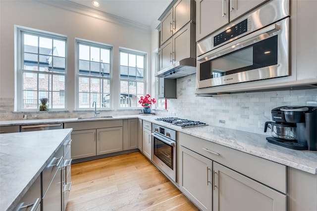 kitchen featuring sink, crown molding, appliances with stainless steel finishes, tasteful backsplash, and light stone countertops