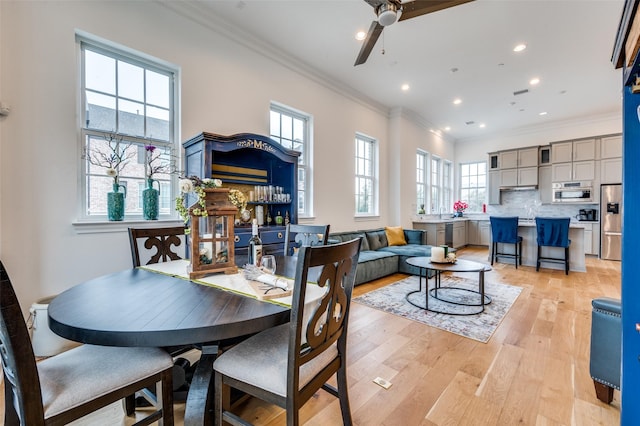 dining area with crown molding, a wealth of natural light, and light wood-type flooring