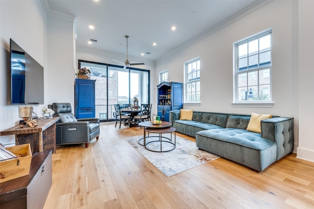 living room featuring ornamental molding, a wealth of natural light, ceiling fan, and light hardwood / wood-style flooring