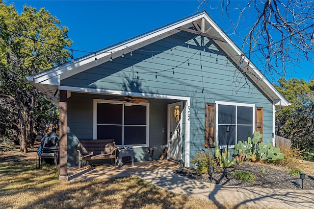 back of property featuring ceiling fan and a yard