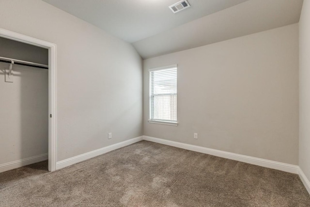 unfurnished bedroom featuring lofted ceiling, carpet floors, and a closet