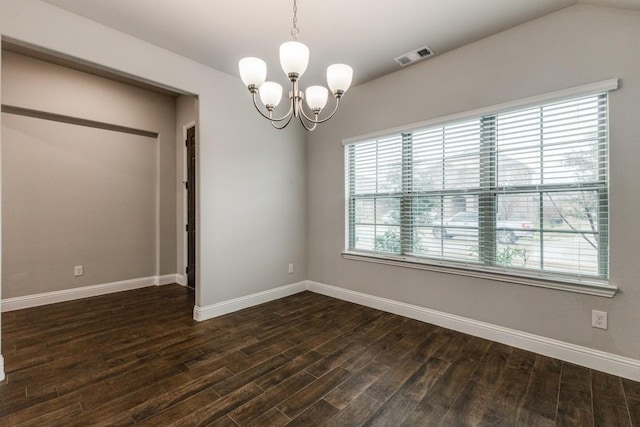 spare room featuring a notable chandelier and dark wood-type flooring