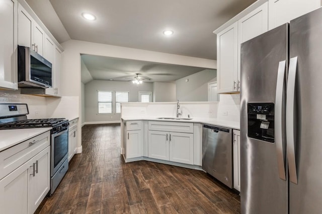 kitchen with appliances with stainless steel finishes, dark hardwood / wood-style floors, white cabinetry, sink, and kitchen peninsula