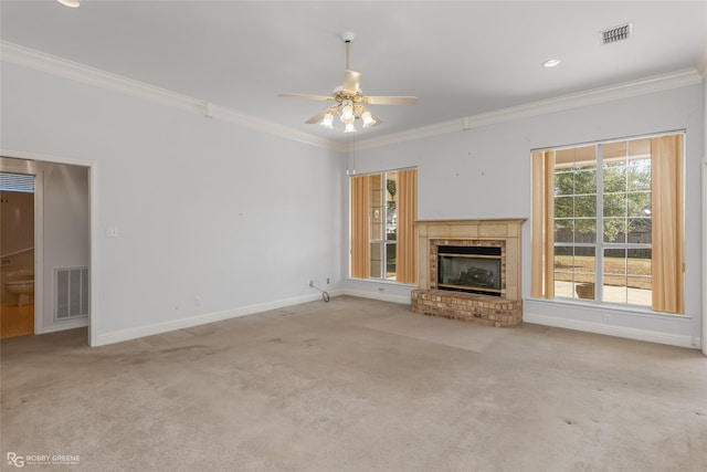 unfurnished living room with crown molding, ceiling fan, a brick fireplace, and light carpet