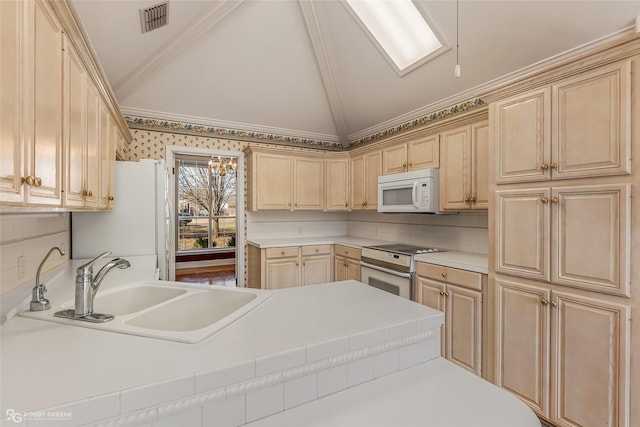 kitchen featuring lofted ceiling, sink, light brown cabinets, and white appliances