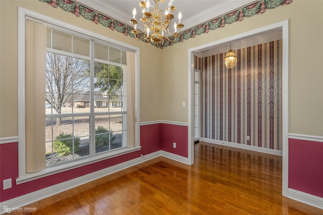 spare room with a notable chandelier, crown molding, and wood-type flooring