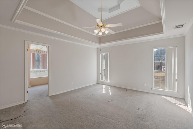 carpeted empty room with crown molding, a wealth of natural light, ceiling fan, and a tray ceiling