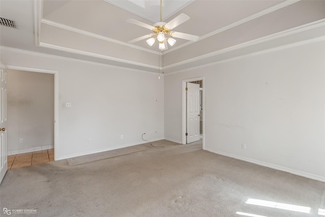 carpeted spare room featuring crown molding, ceiling fan, and a raised ceiling