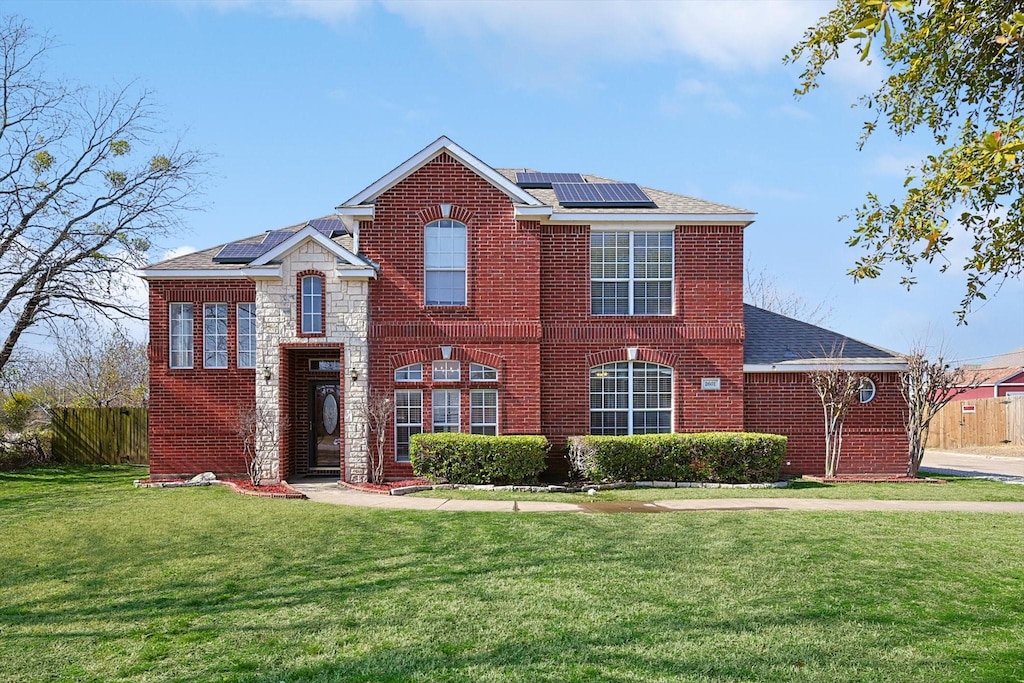 view of front facade featuring a front lawn and solar panels