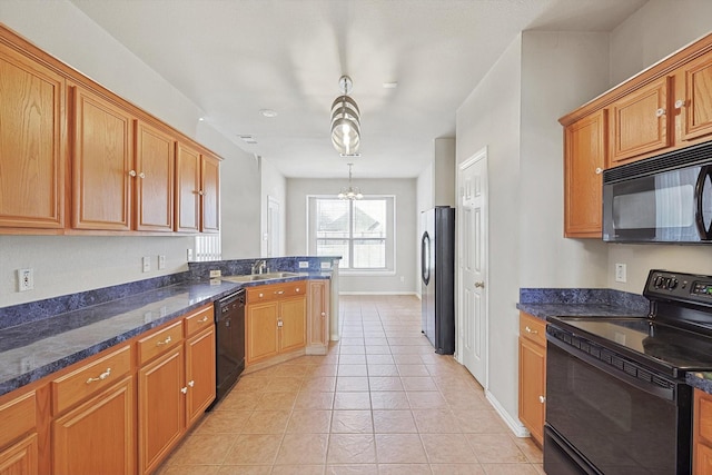 kitchen featuring pendant lighting, sink, dark stone counters, light tile patterned floors, and black appliances