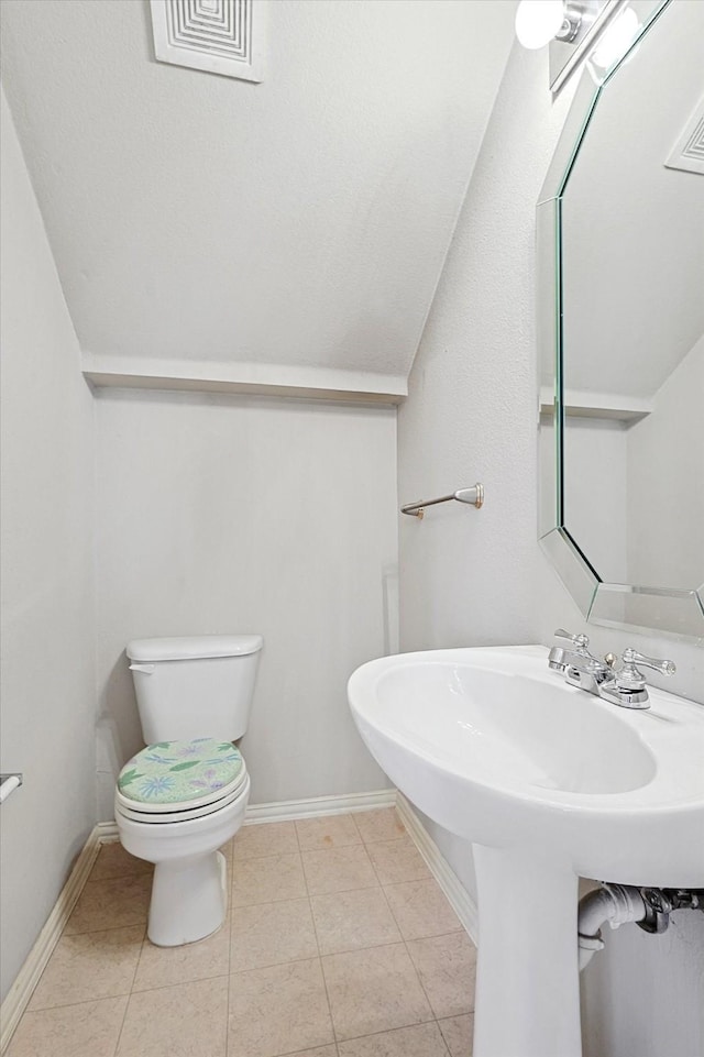 bathroom with lofted ceiling, tile patterned floors, and toilet