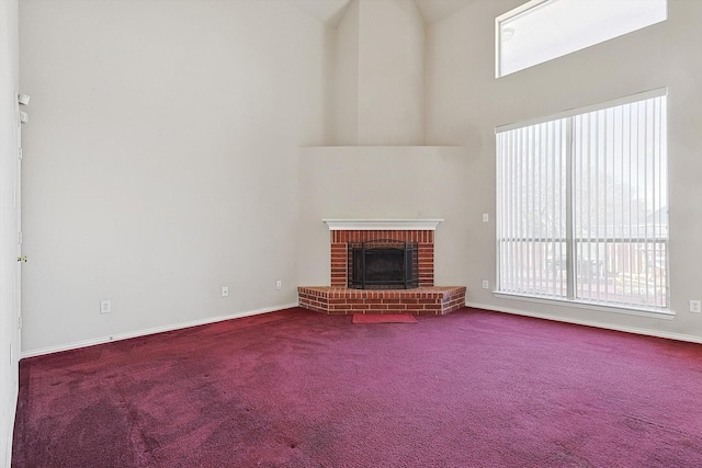 unfurnished living room featuring a brick fireplace, a high ceiling, and carpet